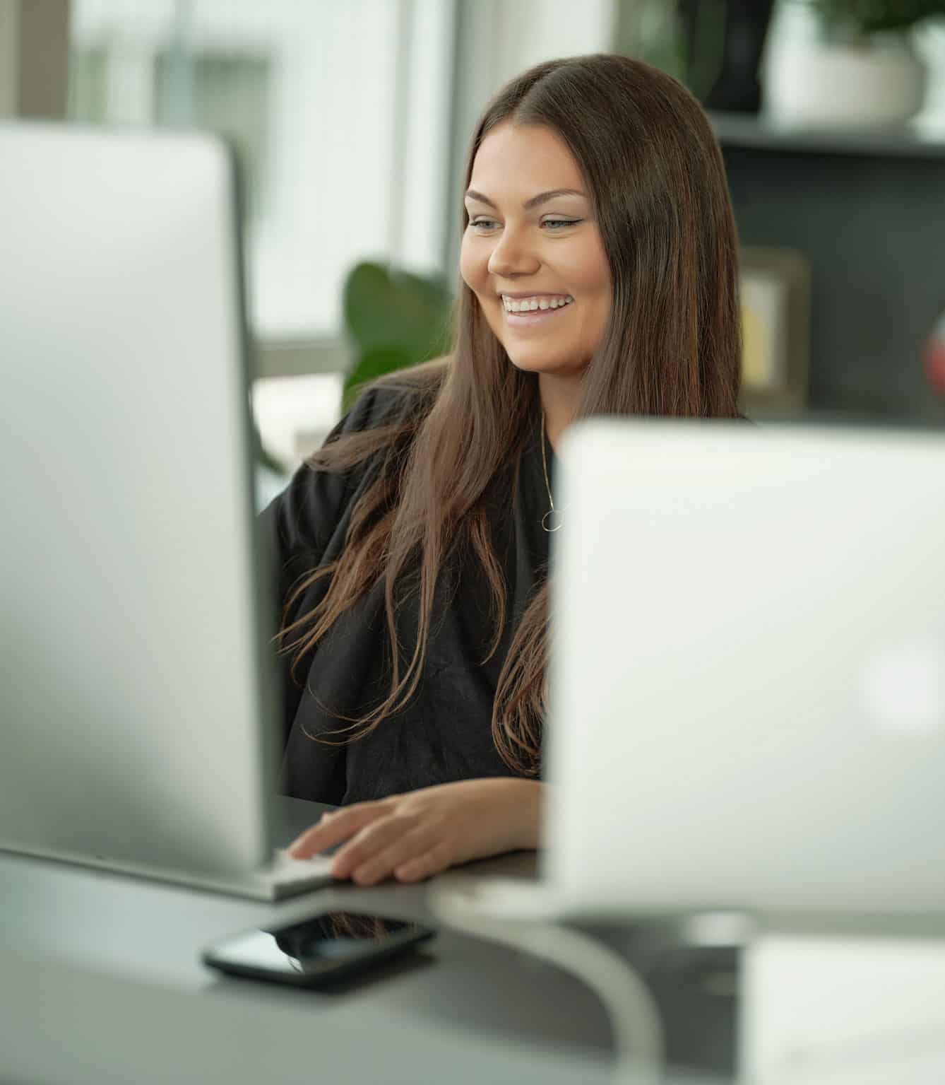 Emilia Jente med brunt hår sitter foran Mac
