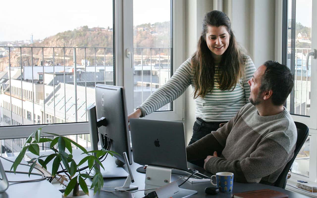 Jente foran pc og gutt drikker kaffe